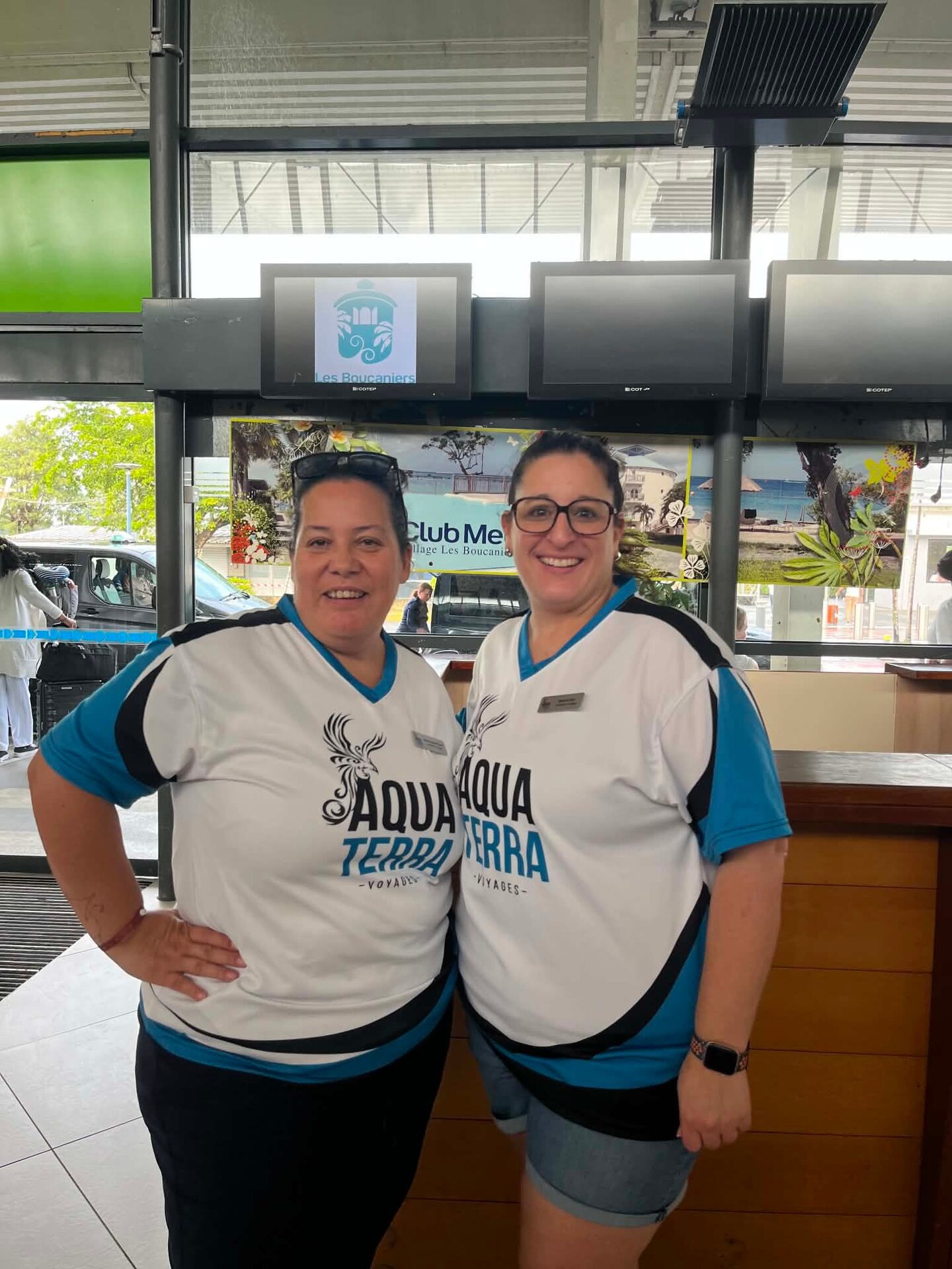 Two AquaTerra advisors in branded shirts at the Martinique airport welcome desk