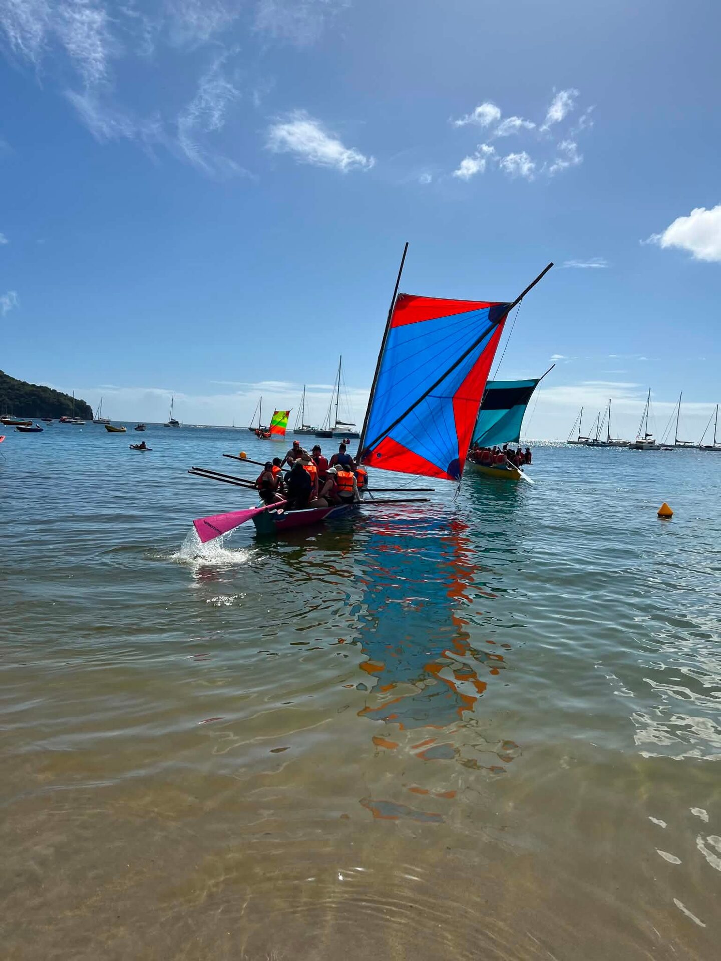 Two Martinique yoles with colourful sails racing in the bay of Les Trois-Îlets