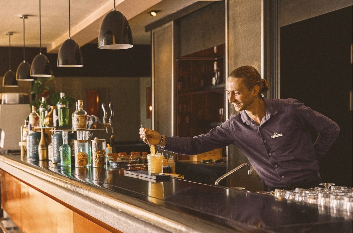 Bartender at Club Med Opio in Provence garnishing an orange cocktail to provide a refreshing experience.