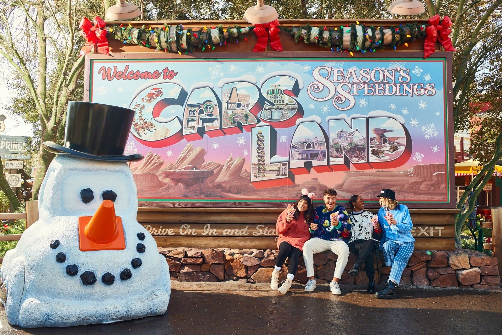 The Cars Land sign dressed for the holiday season with a snowman made of tires
