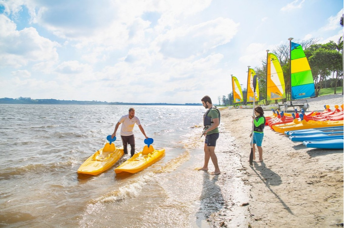 Famille sur la plage au Club Med Lake Paradise, Brésil, prête à embarquer pour une activité kayak sur le lac.