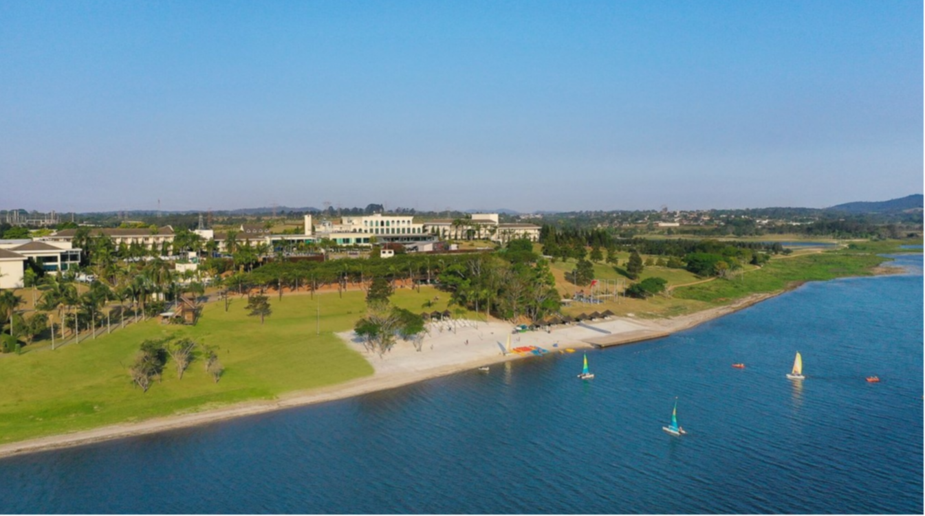 Village of Club Med Lake Paradise in Brazil, featuring a lake, sandy beach, green spaces, and various water activities.