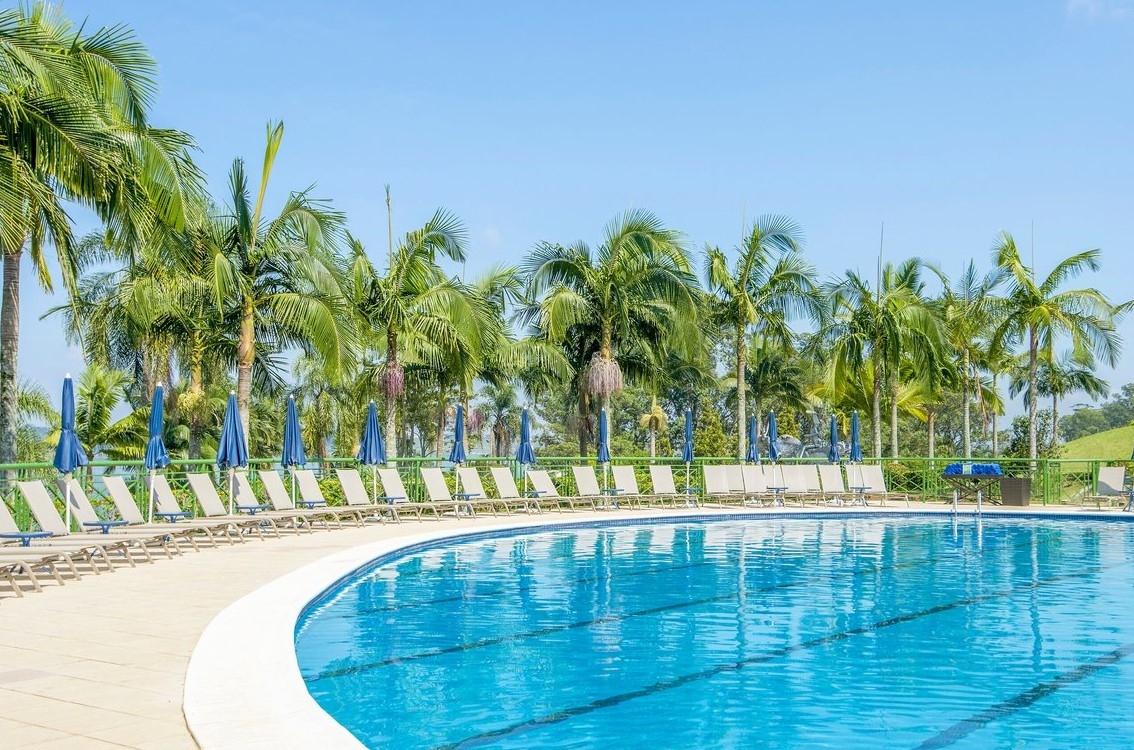 Piscine entourée de chaises longues et palmiers au Club Med Lake Paradise, Brésil, offrant détente et ambiance tropicale.