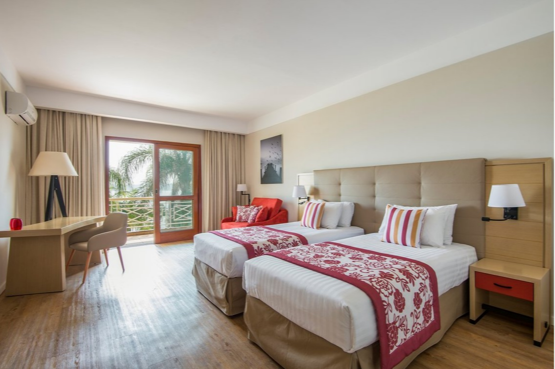 Modern room with single beds and a balcony overlooking palm trees at Club Med Lake Paradise in Brazil.