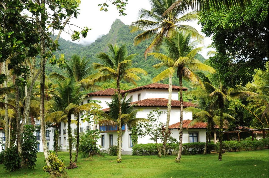 The Club Med Rio Das Pedras resort surrounded by palm trees and overlooked by tropical mountain scenery.