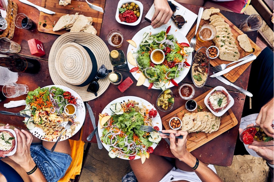 Une famille partage un repas coloré et varié dans un restaurant du Club Med Rio Das Pedras. Une expérience culinaire conviviale.