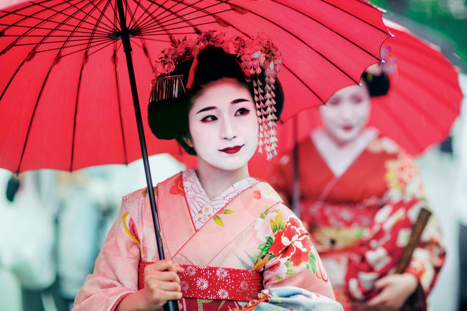 Geishas in kimono under a red parasol, Kyoto