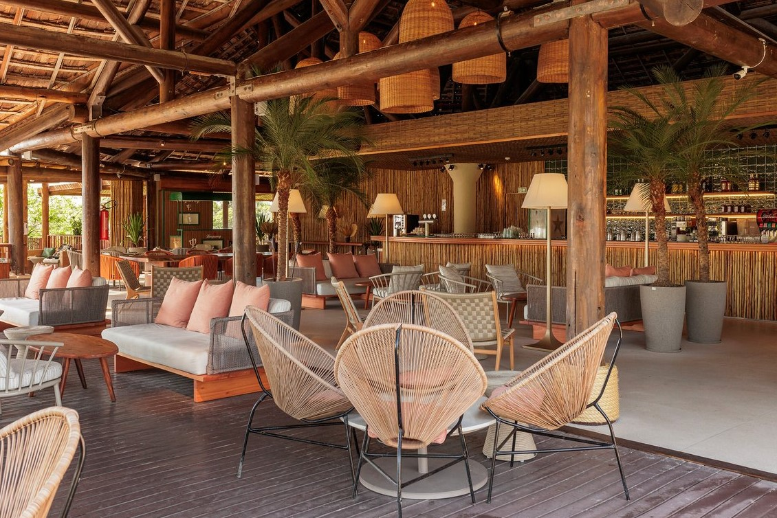 Covered lounge area at Club Med Trancoso, with a bar, armchairs, and sofas, perfect for relaxing evenings.