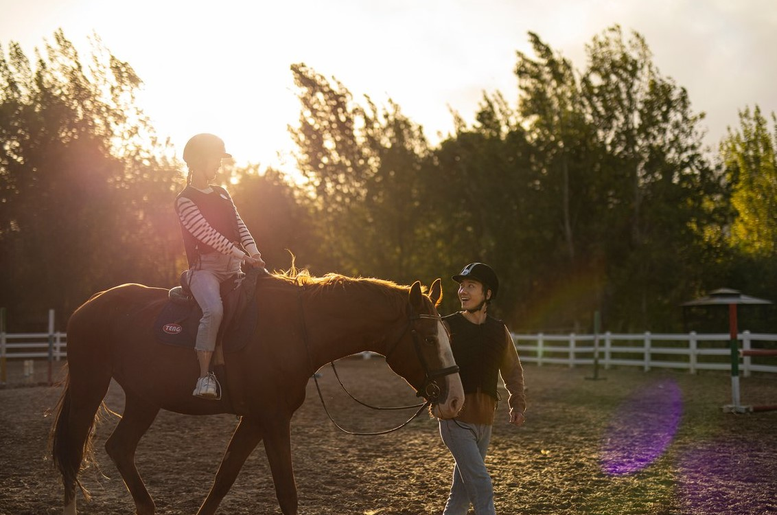 Femme à cheval au Club Med Yasmina, guidée par un instructeur dans le centre équestre, une activité relaxante.