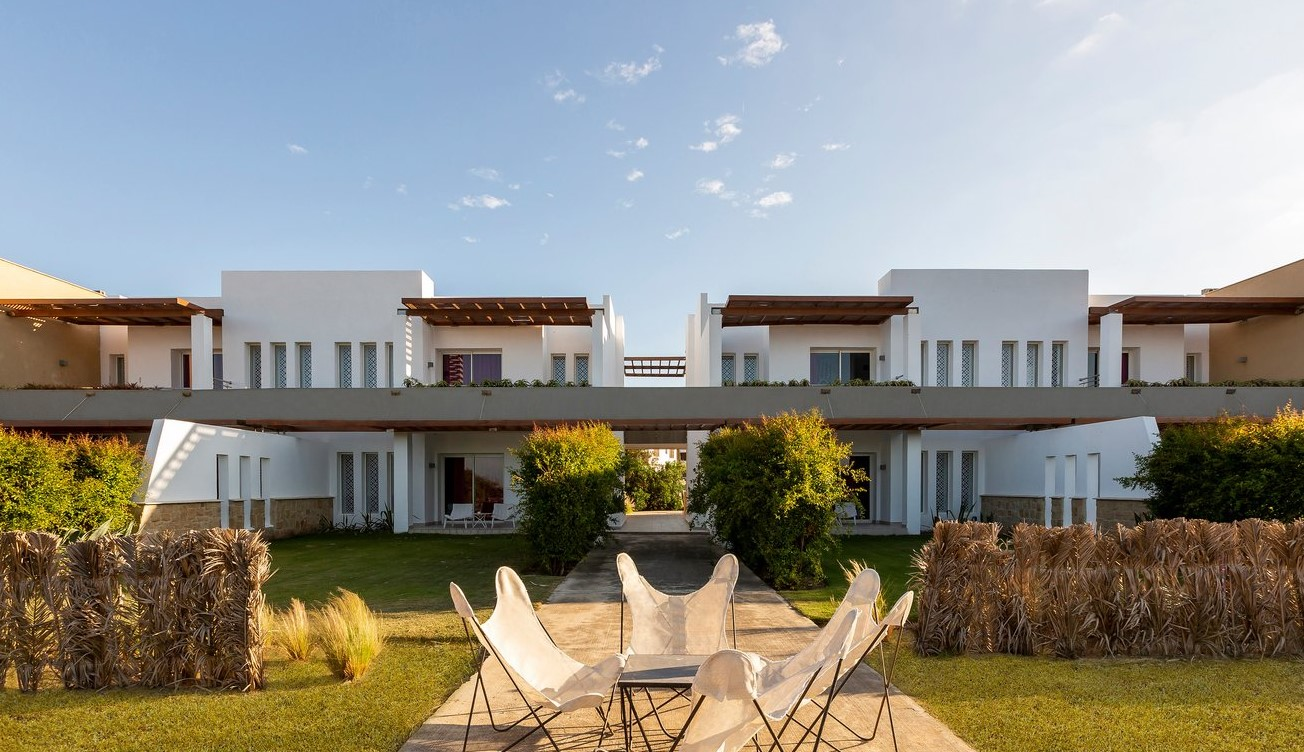 Buildings housing rooms at Club Med Yasmina, featuring covered balconies and lounge chairs, in a serene setting.