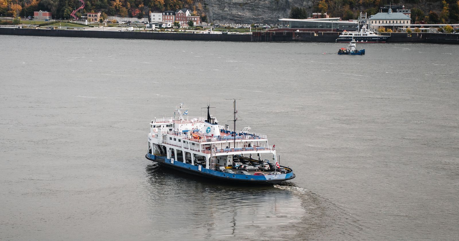 Navire naviguant sur le fleuve Saint-Laurent devant les falaises boisées de Québec aux couleurs d'automne