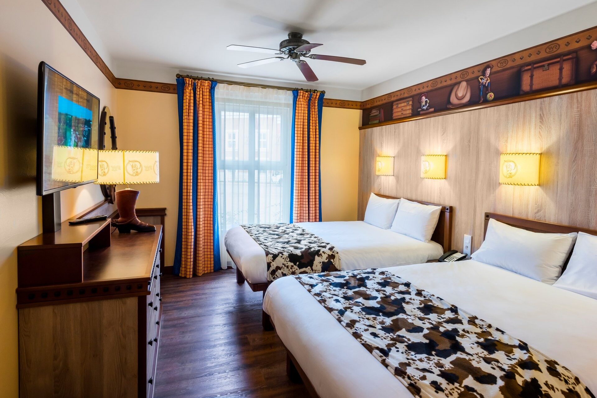Une chambre du Disney Hotel Cheyenne, avec deux grands lits aux couvre-lits imprimés vache et un décor de ranch aux tons chauds. Photo : ©Disney/Pixar.