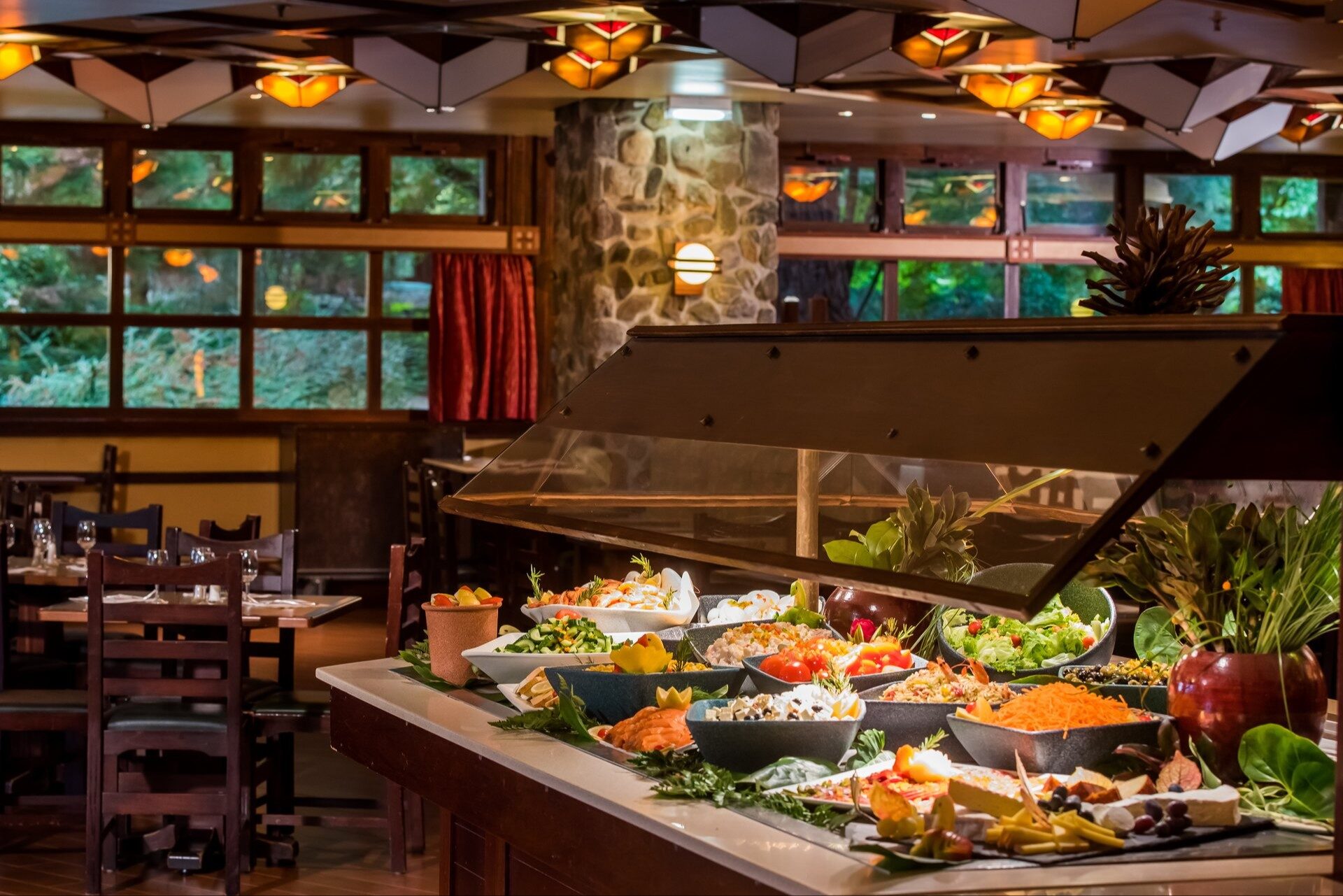 Le buffet de La Cantina, au Disney Hotel Santa Fe, garni de salades et de plats colorés, avec les fenêtres vertes de la salle en arrière-plan.