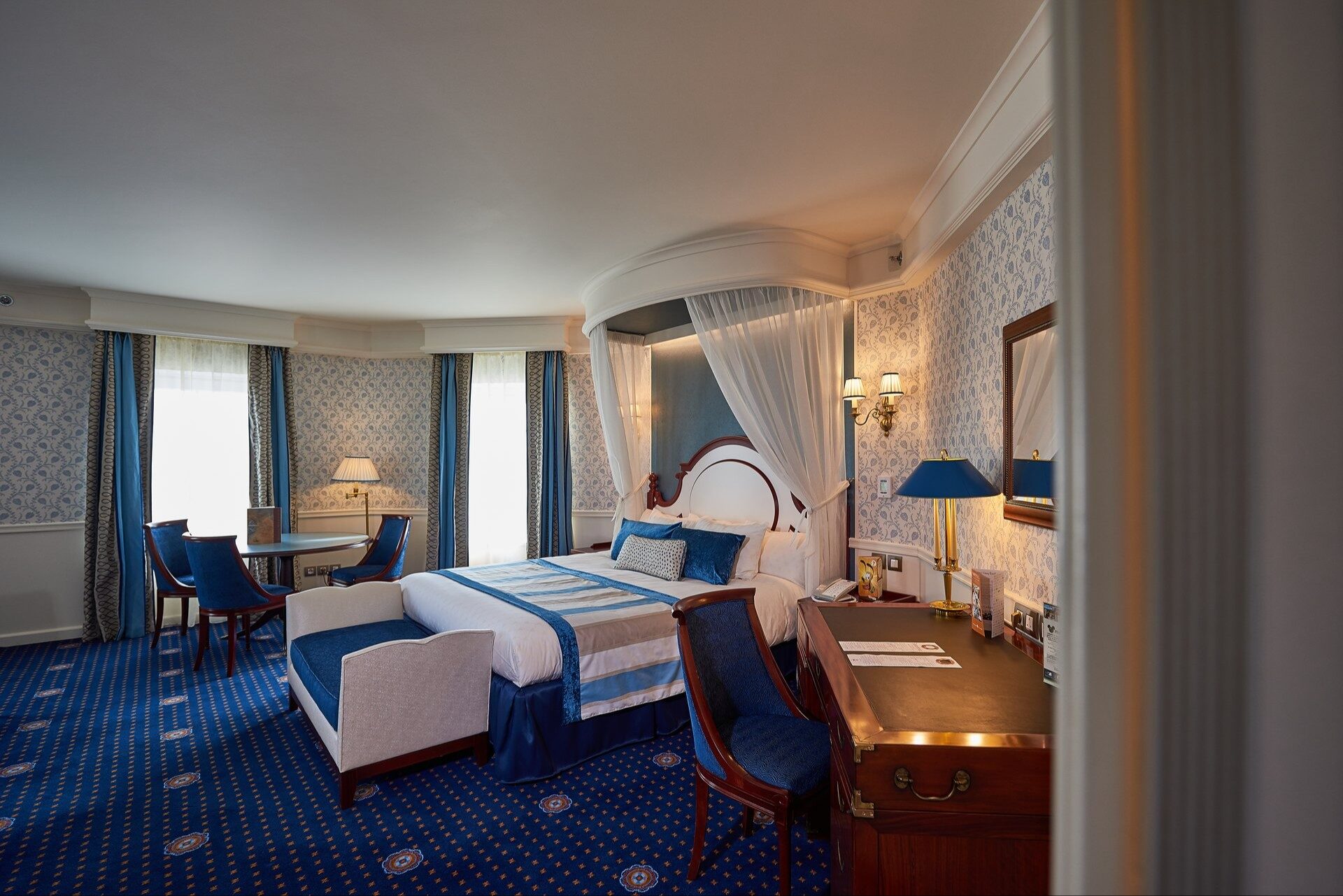 Une suite du Disney Newport Bay Club, avec son lit à baldaquin, ses tons bleu marine et son coin salon près des fenêtres.