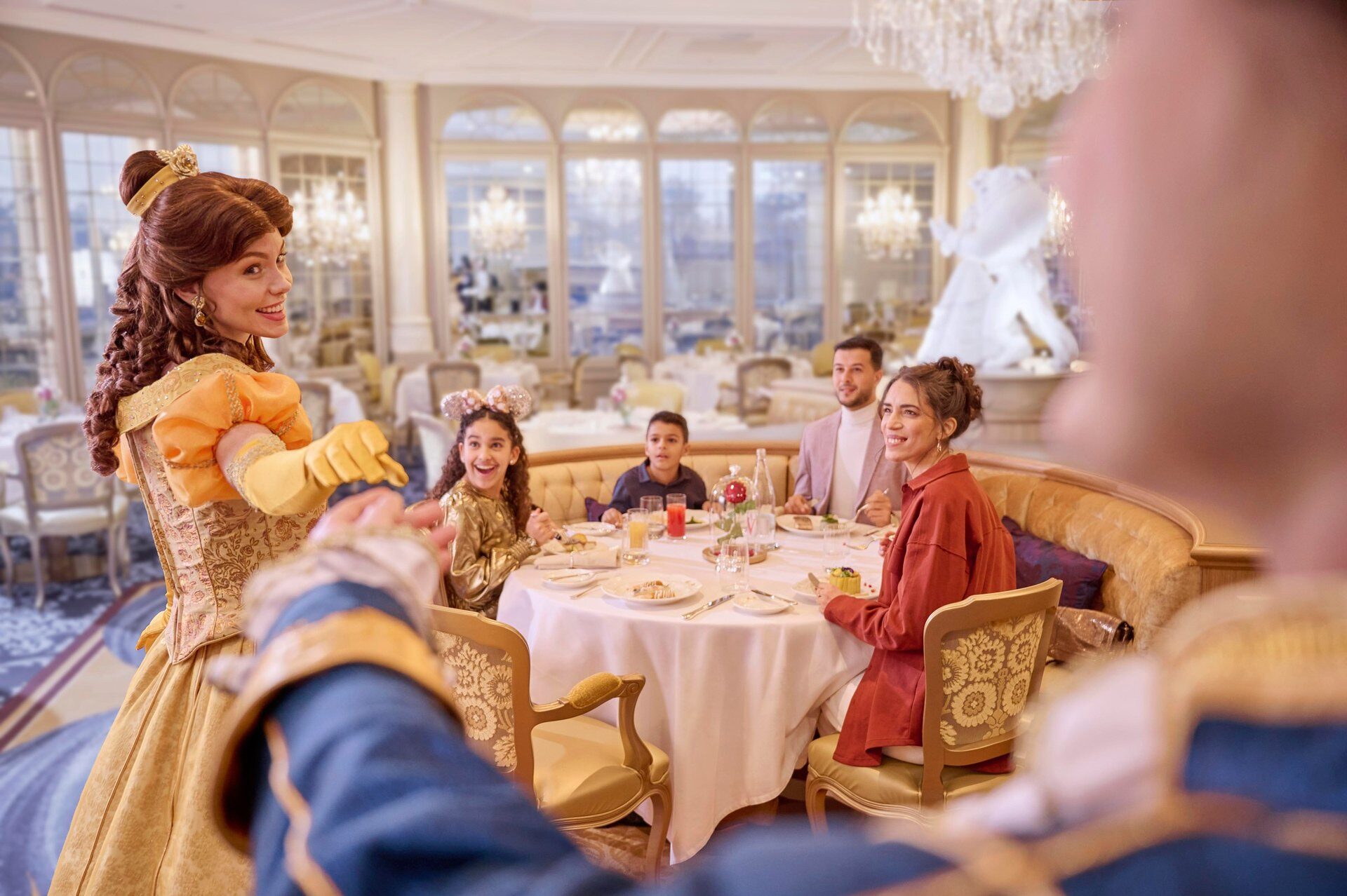 Belle from Beauty and the Beast greets a family at their table in a bright dining room at Disneyland Hotel. Photo: ©Disney. Belle from Beauty and the Beast greets a family at their table in a bright dining room at Disneyland Hotel. Photo: ©Disney.