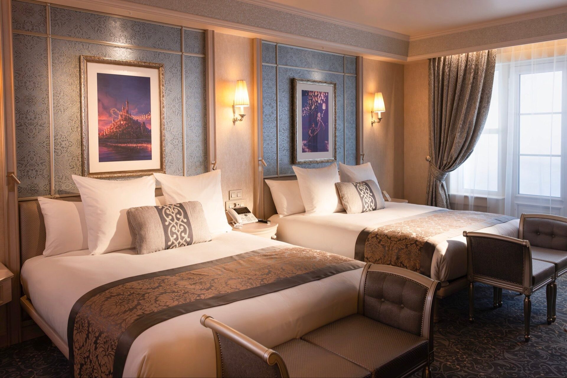 Une chambre Supérieure du Disneyland Hotel à Disneyland Paris, avec deux grands lits, des tons bleu et or et des œuvres d