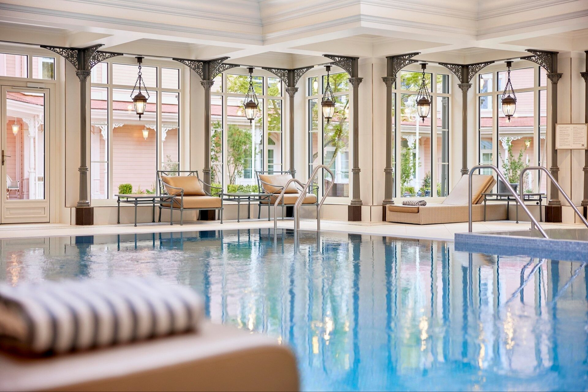 La piscine intérieure chauffée du Crystal Pool du Disneyland Hotel, bordée de grandes fenêtres encadrées de colonnes en fer. Photo : ©Disney.