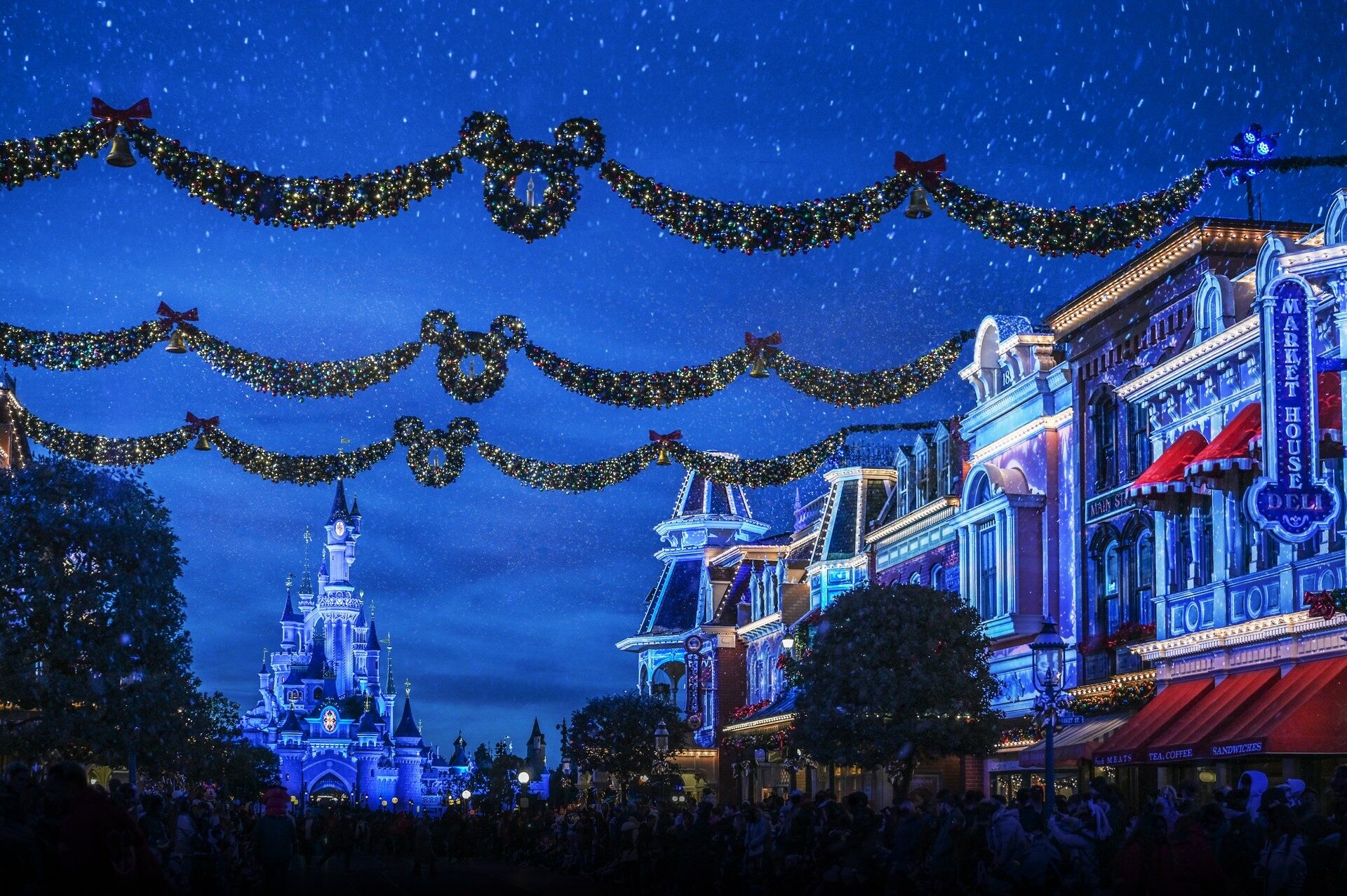 Main Street, U.S.A. décorée de guirlandes pour Noël, un soir d'hiver, avec le château illuminé au bout de l'avenue. Photo : ©Disney. Main Street, U.S.A. décorée de guirlandes pour Noël, un soir d'hiver, avec le château illuminé au bout de l'avenue. Photo : ©Disney.