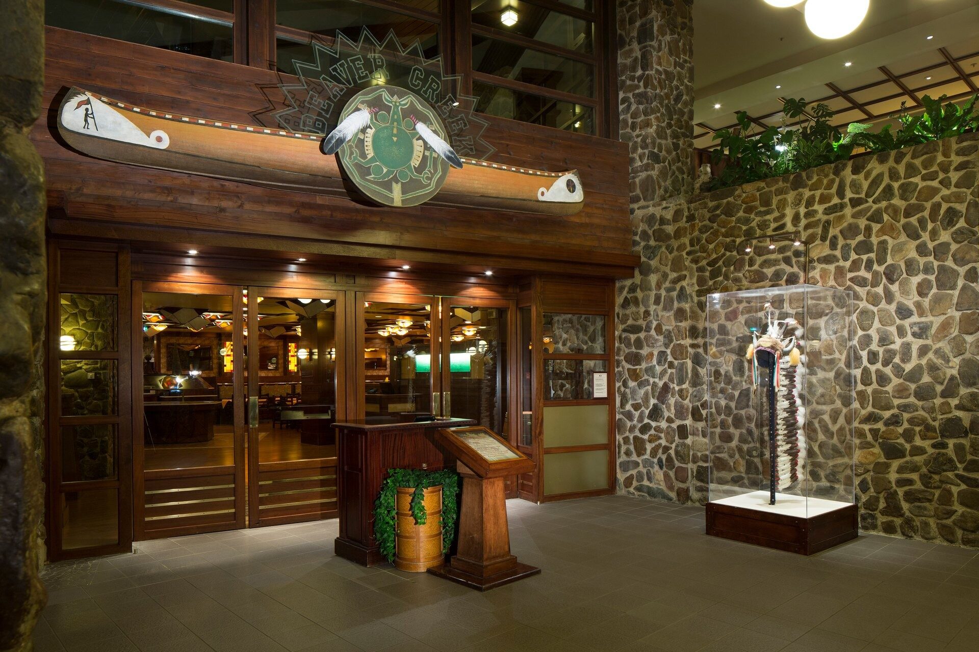 L'entrée du restaurant Beaver Creek Tavern, au Disney Sequoia Lodge, avec son mur de galets, son totem et son grand emblème en bois. Photo : ©Disney.