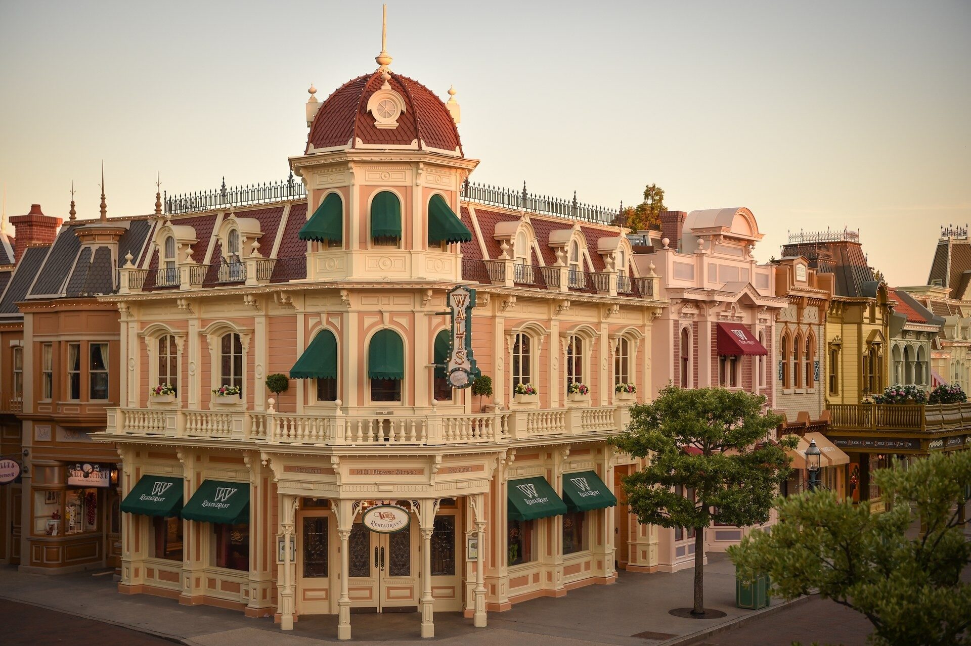 La façade de Walt's – an American Restaurant sur Main Street, U.S.A., au Parc Disneyland, avec ses balcons et son dôme rouge. Photo : ©Disney. La façade de Walt's – an American Restaurant sur Main Street, U.S.A., au Parc Disneyland, avec ses balcons et son dôme rouge. Photo : ©Disney.