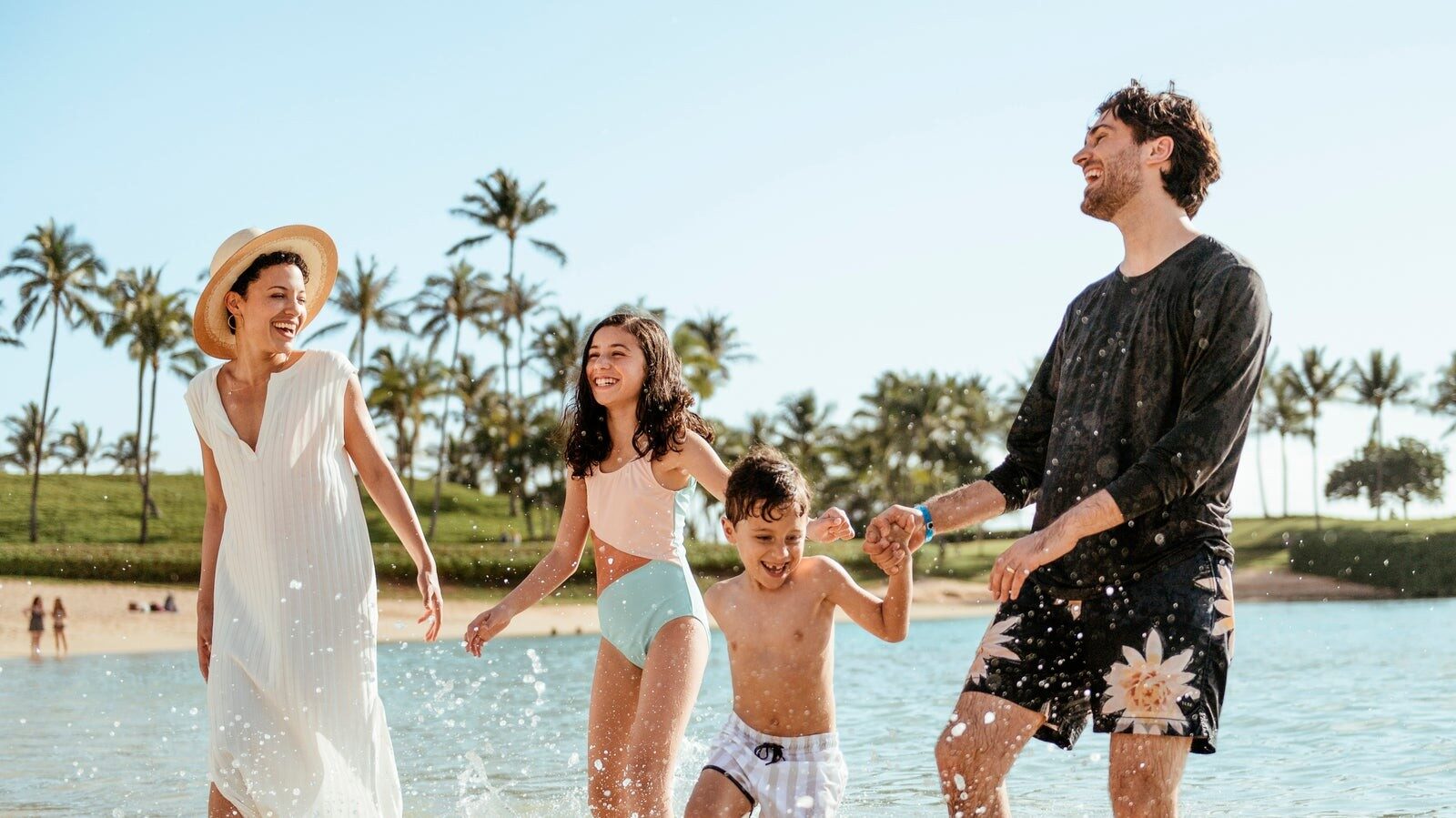 A family wading in the Ko Olina lagoon in front of Aulani, A Disney Resort & Spa