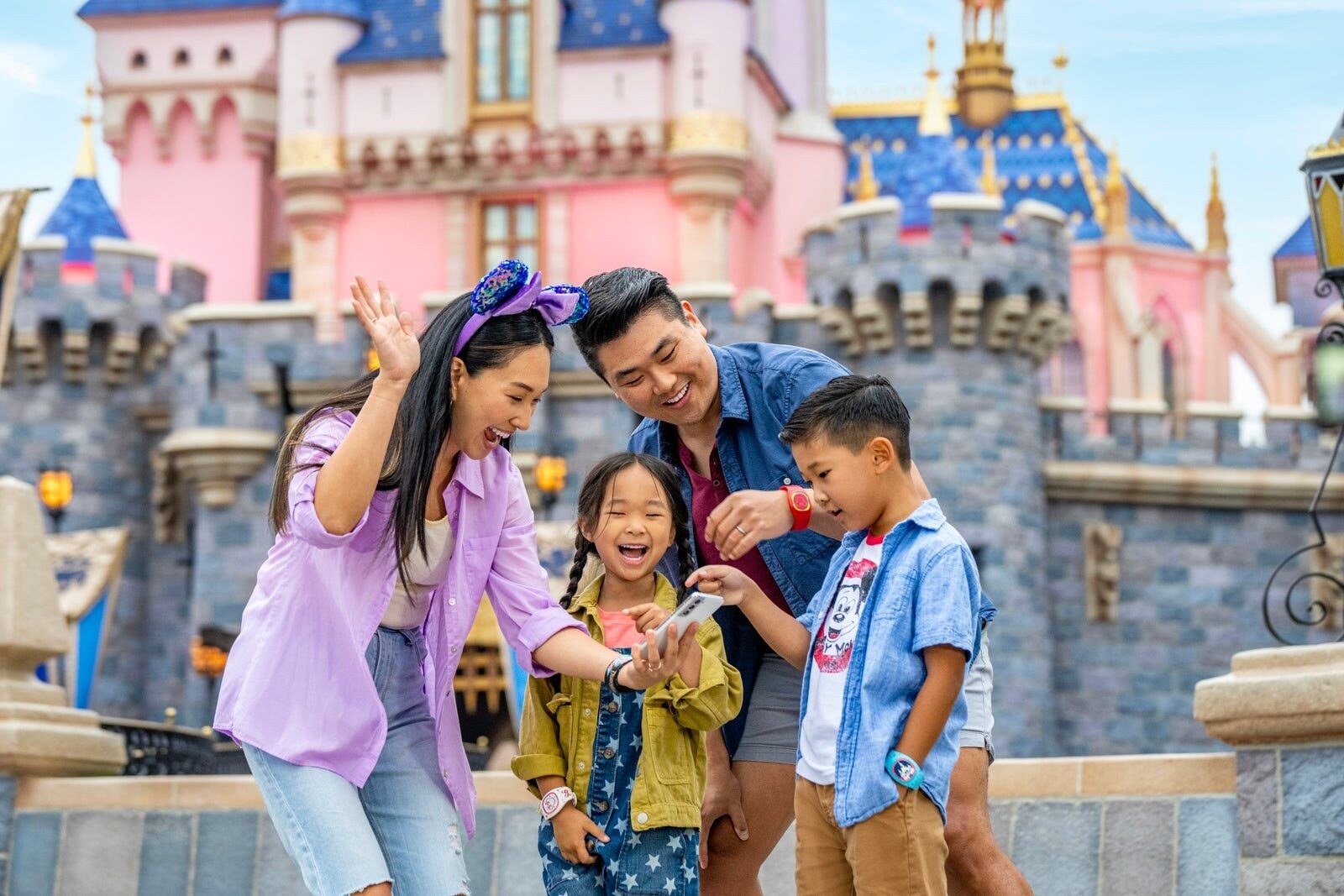 A family posing in front of Sleeping Beauty Castle at Disneyland Park
