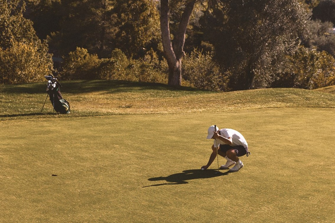 Man placing his ball on the green of the golf course at Club Med Opio in Provence, surrounded by a peaceful Provençal landscape.