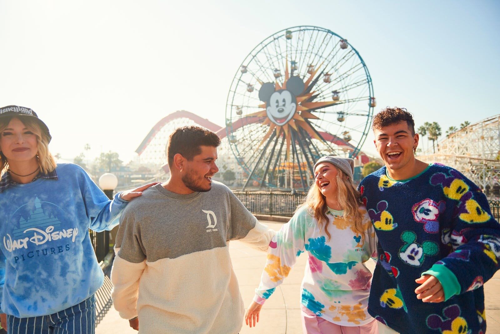 A group of friends walking along Pixar Pier with the wheel in the background