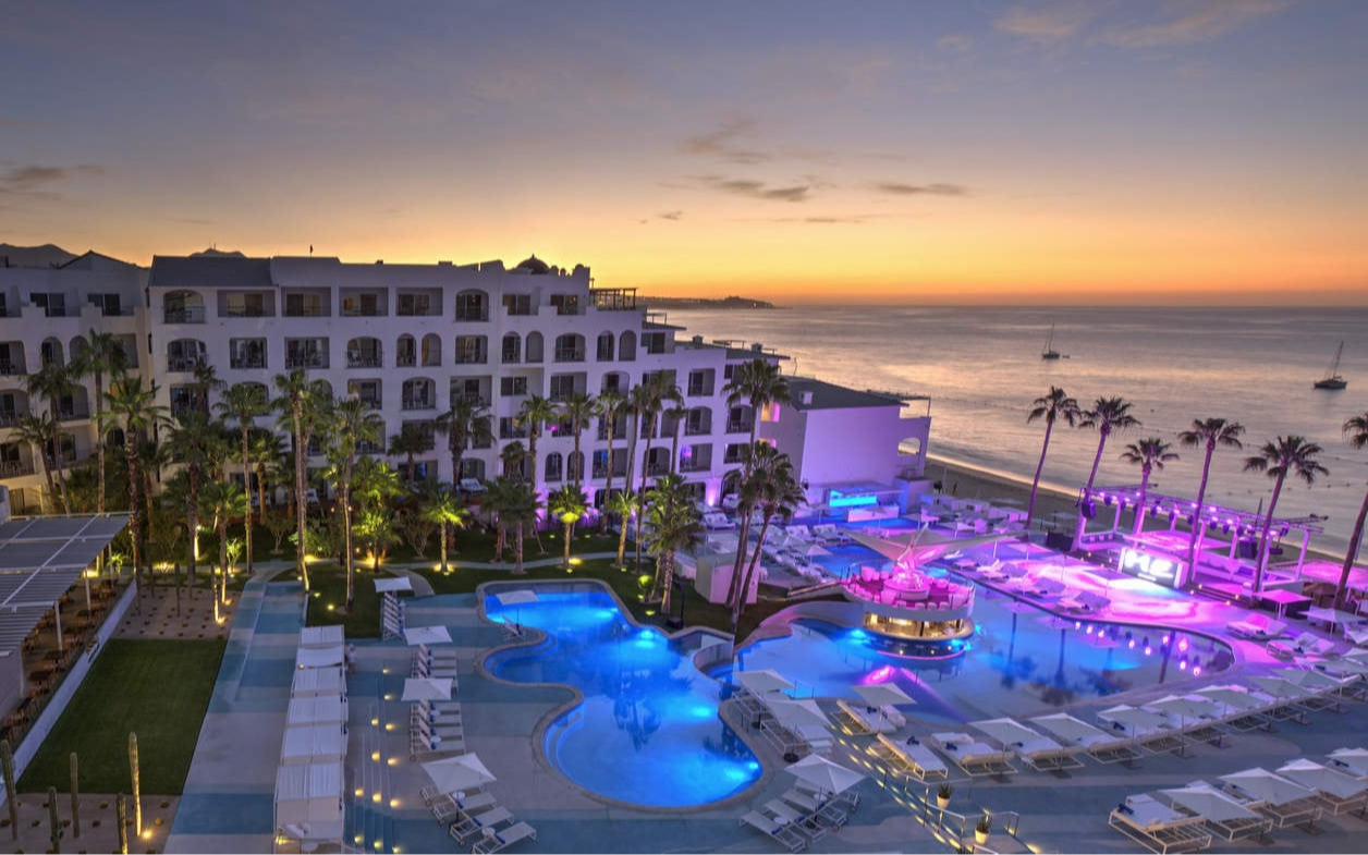 The lit-up pools of ME Cabo at dusk, facing the bay of Cabo San Lucas The lit-up pools of ME Cabo at dusk, facing the bay of Cabo San Lucas