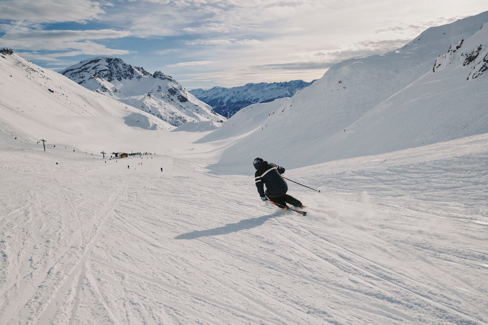 Skieur qui descend une large piste en haute montagne