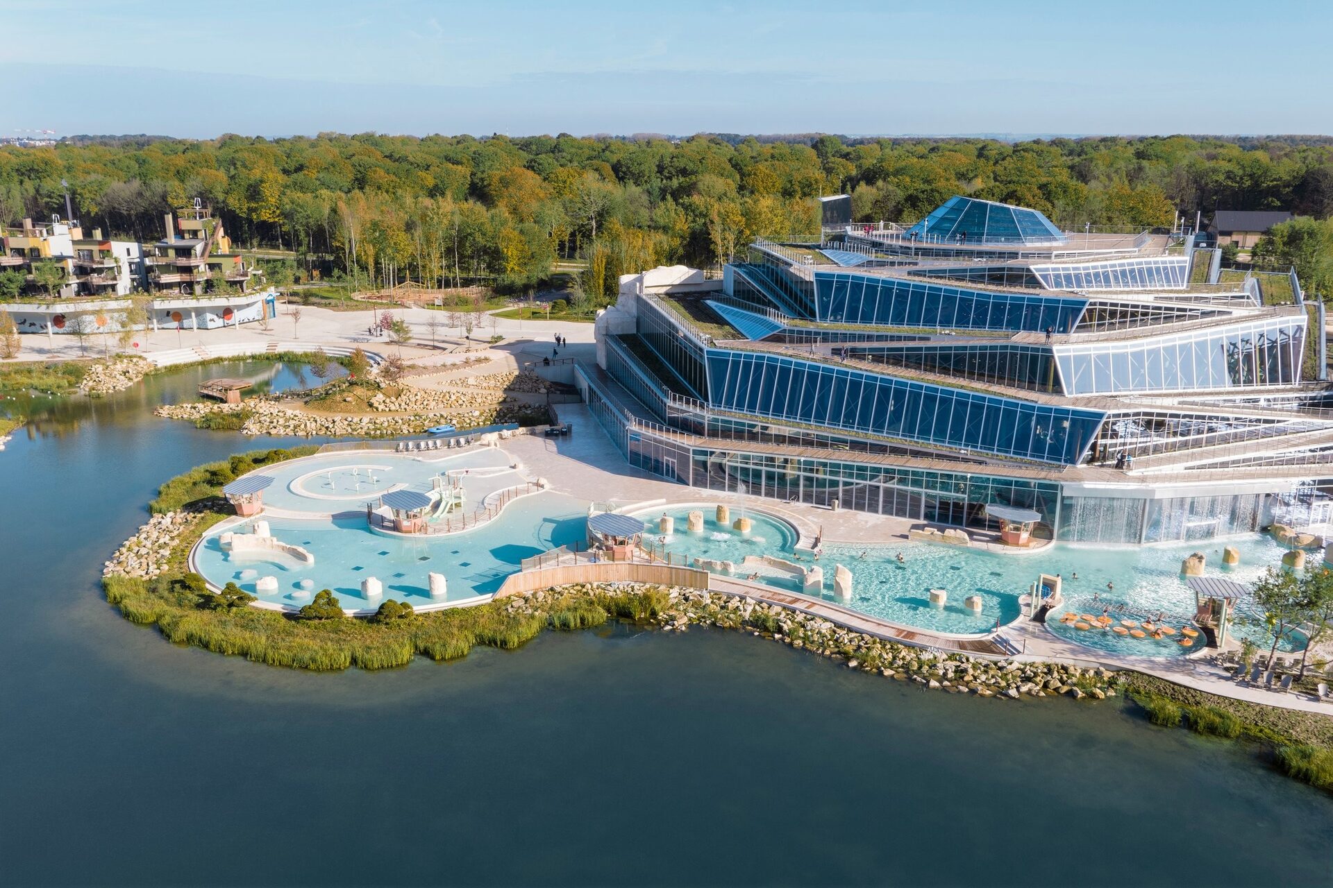 Aerial view of the Aqualagon at Villages Nature Paris, with its outdoor pools beside the lake. Photo: © Aeriallive.